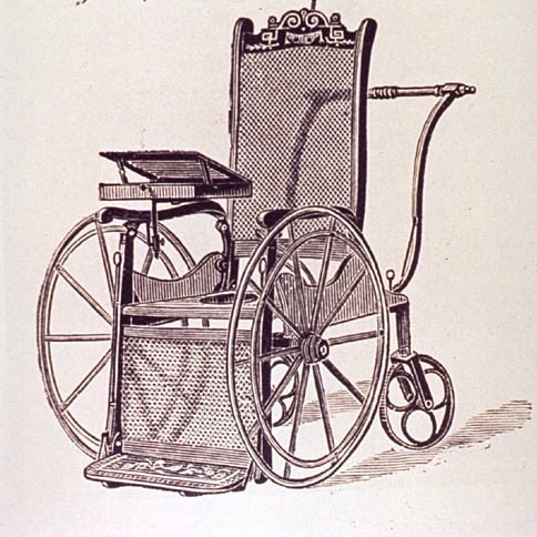 A drawing of an 18th century wheelchair. The two front wheels are large, with two back small wheels. There is a large handle at the back for the person pushing the wheelchair to use. There is also a lap tray and foot rest